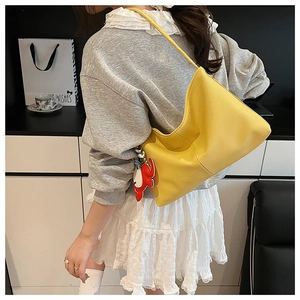 Detail of yellow pebbled leather tote bag with elephant charm and spacious design