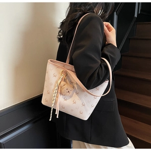 Detail of off-white tote bag with deer prints, pink strap, and cute plush bear charm