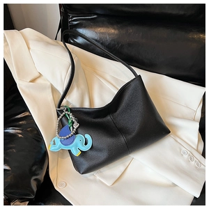 Detailed macro view of black lychee grain leather hobo bag with a blue elephant charm