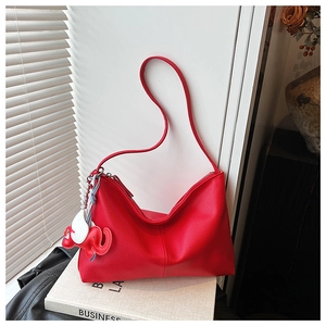 Detail of red lychee pattern leather underarm bag with red elephant charm accessory