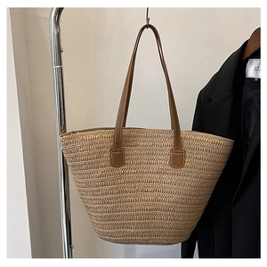 Detail of woven straw tote bag featuring brown leather handles and fine texture