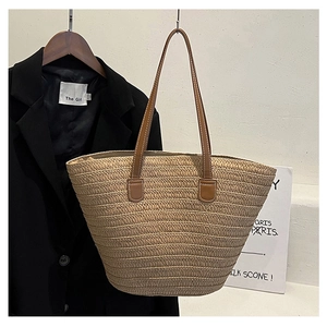 Detailed texture of beige woven straw tote bag with premium brown leather handles