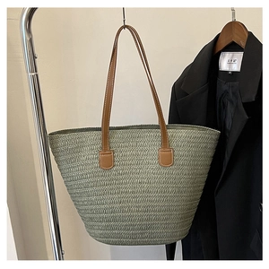 Detail of green straw woven tote with brown leather handles and fine stitching quality