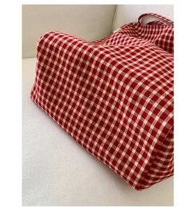 Detailed close-up of red and white gingham canvas tote bag fabric texture and side label