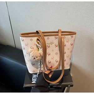 Detail of deer print tote bag featuring pebbled leather texture and plush bear charm