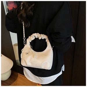 Detail of cream-colored pleated cloud bag featuring pearl pendant and fashion text