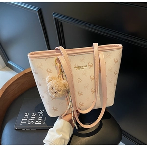 Detail of cream tote bag featuring deer pattern, pink trim, and cute plush bear accessory