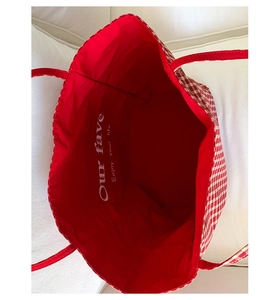 Detail of red and white checkered canvas tote interior with printed lifestyle slogan