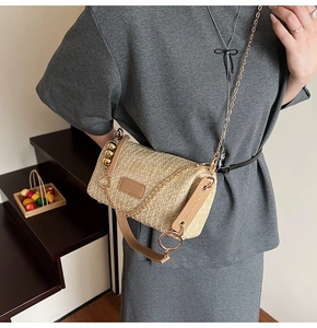 Détail du sac seau en paille tissée avec empiècement cuir et chaîne dorée