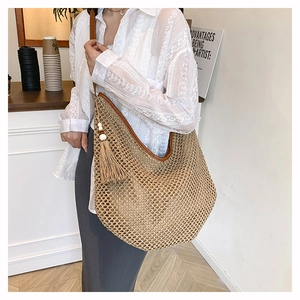 Détail du grand sac à bandoulière en paille avec texture tressée et pompon décoratif