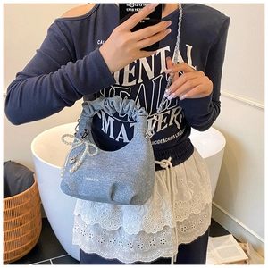 Detail of blue denim textured cloud bag with pearl bow charm and chain strap