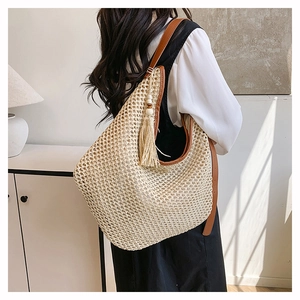 Détail du sac cabas en paille tissée avec bretelles en cuir marron et pompons beiges