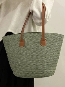 Morandi green woven straw tote bag with brown leather handles worn over the shoulder