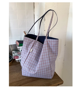 Detail shot of the red and blue plaid canvas tote bag with woven logo and durable shoulder strap