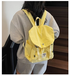 Detail view of bright yellow lightweight nylon backpack with drawstring and flap closure