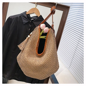 Détail d'un sac à bandoulière en paille tissé main avec finitions en cuir brun et gland