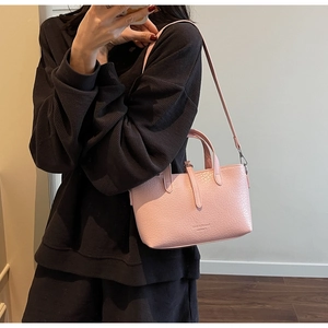 Detail shot of a pink faux-crocodile leather handbag in an indoor mirror selfie setting