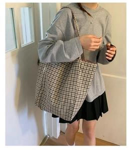 Detail of checkered canvas tote bag showing the fine black and white plaid texture and strap