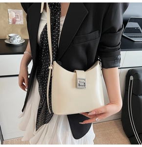 Détail du sac seau blanc crème avec boucle en G argentée porté sur l'épaule