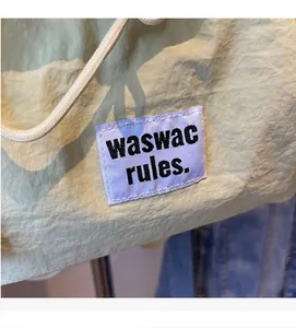 Close-up of light green nylon fabric with a rectangular logo label and drawstring detail