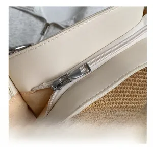 Detail view of the smooth silver zipper and woven texture on a cream straw tote bag