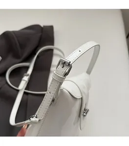 Dettaglio della borsa in pelle verniciata bianca con fibbia in metallo argento e cinturino