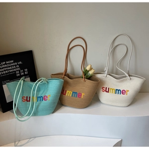 Detail view of woven beach tote bags in mint green and beige with summer embroidery