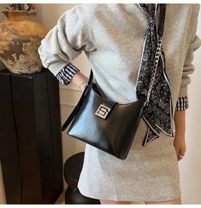Gros plan du sac seau noir mat avec boucle en métal argenté et détail de foulard en soie