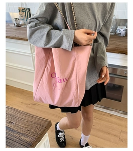 Close-up of pink canvas tote bag with letter print and checkered shoulder strap