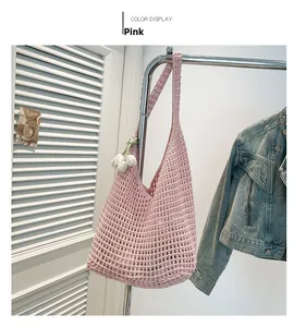 Pink hand-woven crochet mesh tote bag with white tulip charm hanging on a rack