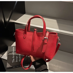 Detail of red crocodile texture on stylish leather handbag with silver buckle and handle