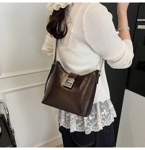 Détail du sac à bandoulière en cuir marron foncé avec une boucle en métal argenté rectangulaire