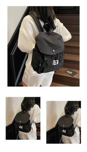 Detail of black nylon backpack featuring a drawstring closure and stylish waswic label
