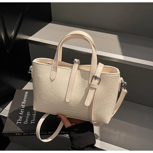 Detail of cream white faux leather bag with textured ostrich grain and silver hardware