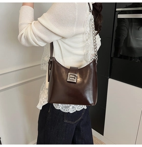 Détail d'un sac à bandoulière marron brillant avec boucle argentée et bandoulière chaîne