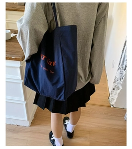 Navy blue canvas tote bag detail showing orange rave lettering and street style design