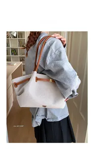 Detail of a large canvas tote bag with brown leather straps shown from a back-view perspective