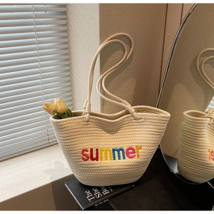 Detail of cream woven beach tote bag with colorful summer embroidery on a book