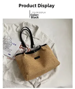Close-up of woven straw tote bag with black leather straps and metal hardware detail