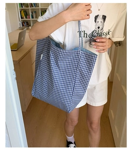 Close-up of blue and white checkered canvas tote bag with side label on shoulder strap