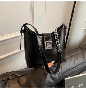 Détail du sac en cuir noir brillant avec boucle G argentée et bandoulière chaîne