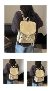 Detail view of a beige canvas backpack showing the drawstring closure and woven brand label