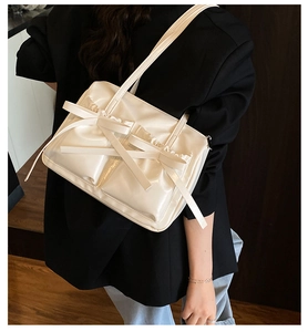 Creamy white bow shoulder bag with pleated ruffles shown on model from the back view