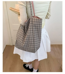 Close-up of black and white checkered canvas tote bag with brand label and pink lining