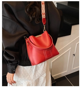 Detail of red bucket bag with wide geometric pattern strap and gold-tone hardware
