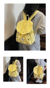 Detail view of bright yellow water-resistant nylon backpack featuring buckle flap and side pockets