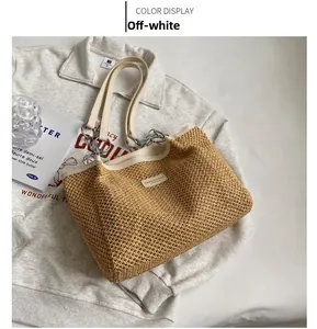 Detail of creamy white straw tote bag featuring fashion metal chain leather handles