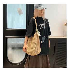 Detail of hand-woven hollow mesh shoulder bag with a white tulip pendant decoration