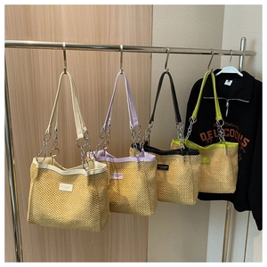Selection of colorful woven straw tote bags with chain straps in cream, purple, and green