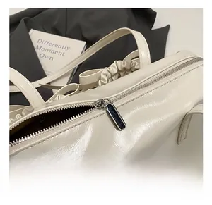 Detailed close-up of cream white leather bag featuring a silver metal zipper and smooth stitching